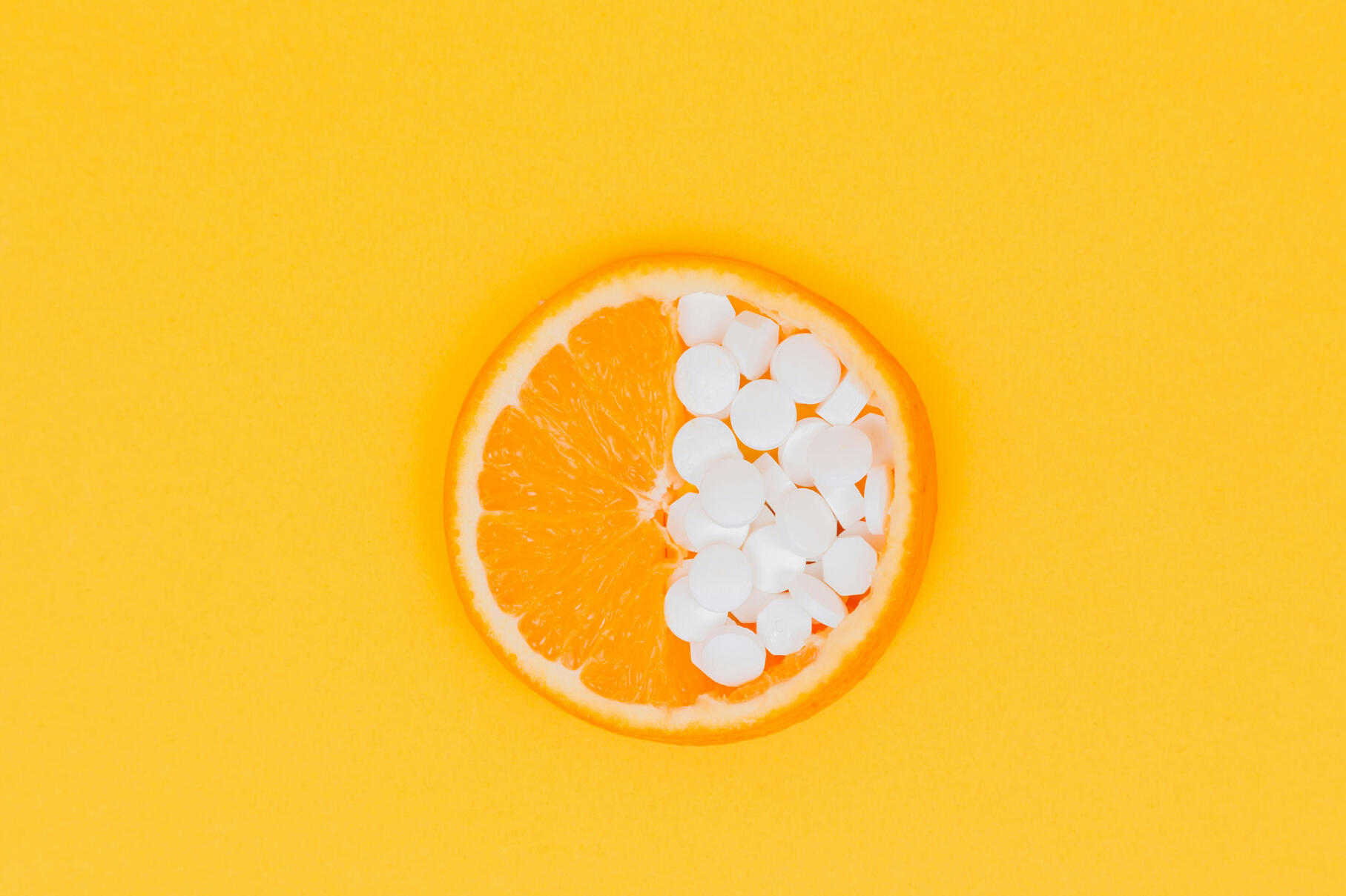 Orange cut in half with half of area filled with pills